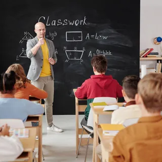 A teacher standing near a chalkboard in a classroom